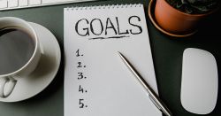 Goals written on notepad on green desk